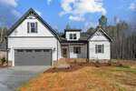 Nestled at 1151 Shonele Lane, this modern two-story house boasts white siding and dark trim. With a gabled roof, a two-car garage adorned with dark doors, and a cozy porch, it stands gracefully against a backdrop of trees under a partly cloudy sky in the picturesque town of Stem.