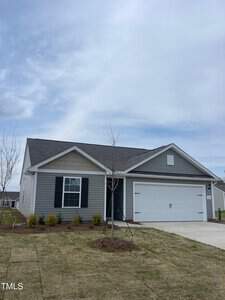 Nestled on 105 Long Green Way, this single-story gray house in Oxford features a gabled roof and white trim. A double garage door complements the small front yard, where a young tree and shrubs thrive under an overcast sky with light clouds.