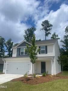 Located at 304 Rhino Bend in Oxford, this two-story modern house boasts a light exterior and features a two-car garage with a small tree adorning the front yard. The sky is partly cloudy, framed by tall trees standing gracefully in the background.