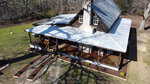 Aerial view of a rustic wooden house at 2603 Moss Ledford Road, Franklinton, featuring a metal roof and wraparound porch. Surrounded by bare trees and a grassy yard, a stone pathway leads to the entrance while shadows of branches stretch across the roof and lawn.