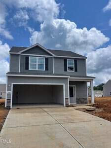 Located at 106 Scoville Street in Oxford, this newly constructed two-story house boasts gray siding and a dark gray roof. It features white trim, black shutters, and a stone accent on the lower facade. A double garage sits in front, and the freshly paved driveway complements the partly cloudy sky.