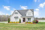 Located at 2514 Jessis Court in Franklinton, this modern two-story white house features dark roofing and a spacious lawn. The inviting front porch is adorned with chairs and framed by neatly trimmed shrubs and small trees, set against a backdrop of a partly cloudy blue sky and a serene pond.