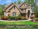 Situated in Youngsville, this large brick house at 4004 Windchime Lane features a charming front garden and is surrounded by trees. The image includes text overlay that reads "Heated Inground Pool!.