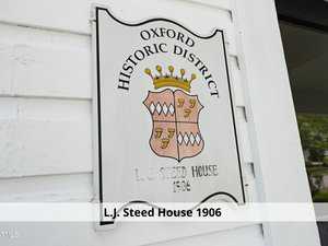 Sign on a white building with a crest and the text "Oxford Historic District, L.J. Steed House, 1906" engraved on it. A horizontal banner below reads "L.J. Steed House 1906.