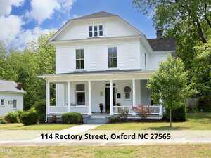 A white, two-story house with a large porch and greenery surrounding it on a sunny day. The address "114 Rectory Street, Oxford NC 27565" is displayed at the bottom of the image.