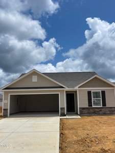 Located at 102 Scoville Street in Oxford, this single-story house boasts a sloped roof and a two-car garage under a partly cloudy sky. With beige siding and stone accents, the new construction features a concrete driveway leading to the garage, surrounded by bare ground.