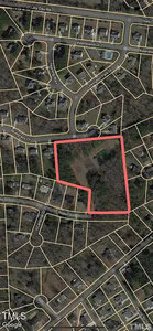 Satellite map of a residential area with streets and houses. A large wooded plot is outlined in red, bordered by Robin Rd and Burgess Dr. Surrounding properties and roads are visible, with tree coverage and open land.