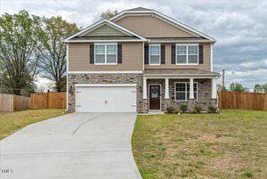 Located at 2766 Spring Valley Drive, this charming two-story house in Creedmoor boasts beige siding and stone accents, a two-car garage, and a concrete driveway. The grassy front yard leads to a cozy porch while the fenced backyard offers views of towering trees.