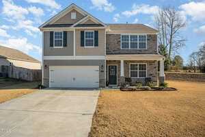 Nestled on 2760 Spring Valley Drive in the serene suburb of Creedmoor, this two-story house boasts a stone and siding exterior. It features a two-car garage and a charming covered front porch. The manicured lawn and clear sky enhance the home's tranquil atmosphere.