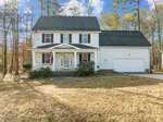Located at 2786 Clifton Avenue in Creedmoor, this charming two-story white house features a welcoming front porch, black shutters, and a double garage. The American flag waves proudly near the entrance. Surrounded by trees, it rests under a blue sky with scattered clouds while the lawn is mostly brown.