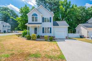Located at 201 Korbin Court in Creedmoor, this charming two-story house boasts light blue siding, a gabled roof, and a single-car garage. The inviting front porch overlooks a manicured lawn with shrubs, set in a picturesque suburban neighborhood beneath a clear blue sky.