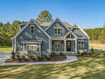 This modern two-story house on 3533 Bruce Garner Road features blue-gray siding, stone accents, and a gabled roof. With its spacious front porch and large windows, the property in Wake Forest is surrounded by a well-maintained lawn and bordered by trees.