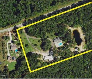 Aerial view of a large wooded property outlined in yellow. The area includes a house with a blue pool, a pond, and green lawns. A road runs along the top edge, and neighboring properties are visible to the left.