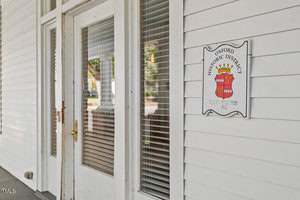 A white building with a partially glass door and windows. Next to the door is a sign reading "Oxford Historic District" with a crest featuring a handshake, two red stars, and the year 1757.