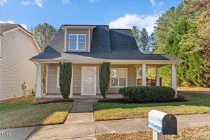 Nestled on 100 York Drive, this charming two-story house in Oxford features a gabled roof and covered porch. Surrounded by trimmed shrubs and a neatly mowed lawn, a mailbox stands at the front under the sunny sky, framed by a picturesque backdrop of trees.
