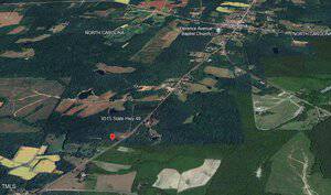 Aerial view of a rural area showing parts of North Carolina and Virginia. The image highlights fields, forests, and a few buildings. A marker points to 9515 State Hwy 49 and labels Florence Avenue Baptist Church. Roads and green spaces are visible.