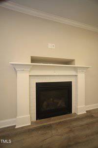 A modern fireplace with a white mantel and beige tile surround set against a light gray wall. A small niche is located above the mantel, and there are two electrical outlets on the wall above the niche.