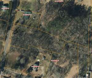 This is an aerial view of a wooded area with houses nearby. Streets are labeled, including Oak Ridge Street, Owens Street, and Oxford Street. Property lines are outlined in yellow. A black arrow is marked on the image.