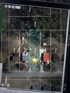 A satellite map view shows a residential area with several houses. The properties are outlined, and a yellow star is placed on one lot towards the center. Trees surround the area, and a street runs horizontally at the bottom.