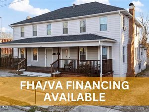 A two-story white house with a porch and dark roof is shown at 121 Hamilton Street, Henderson. The foreground displays the text "FHA/VA FINANCING AVAILABLE" in large white letters over an orange background. The sky is partly cloudy.