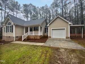 Located at 4050 Brooksdale Drive in Franklinton, this charming single-story house features beige siding and a dark roof. A cozy front porch with white railings and a small stairway welcomes you, while the single garage and driveway complement the tree-lined, grassy lawn.