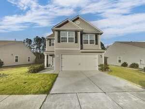 Located at 2053 Alderman Way in Creedmoor, this two-story house features light gray siding and dark shutters. It boasts a two-car garage and a manicured front lawn. The concrete driveway complements the home, which is surrounded by similar houses under a partly cloudy sky.