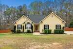 A yellow, single-story house at 1638 Crystal Lane boasts a dark roof, white trim, and symmetrical windows. The front entrance with steps is surrounded by neat shrubs. Its fenced yard with trees stands elegantly under the blue sky, creating a serene stem of suburban charm.