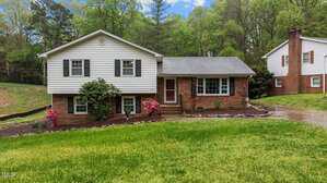 Nestled at 505 Forest Road, this Oxford split-level home boasts a charming combination of white siding and brick exterior. A cozy front porch invites you in, while a curved driveway gracefully leads through the lush green lawn to the entrance, framed by tall trees in the background.