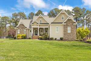 Located at 2000 Silverleaf Drive in Youngsville, this large, two-story house features a blend of stone and light-colored siding on a well-maintained lawn. The front boasts gabled roofs and a covered porch with steps leading up. Trees and a clear sky enhance the scenic backdrop.