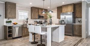 Modern kitchen interior with wooden cabinets, a white island with two stools, stainless steel appliances, and light countertops. A window with shutters is on the left, and plants are placed on the island and counters for decoration.