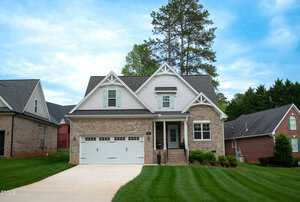 A two-story suburban house at 409 Eagle Court in Henderson with brick and light gray siding, a double garage, front porch with columns, green lawn, and neighboring houses on both sides under a partly cloudy sky.