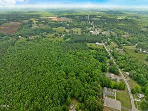 Aerial view of a rural area near 15 US Highway in Stovall, with dense forest, open fields, and scattered houses. Roads wind through farmland and patches of trees visible in the distance under a partly cloudy sky.