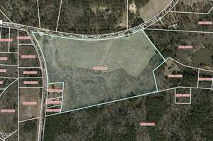 Aerial view of a large, irregularly shaped parcel of land outlined in blue, bordered by Rock Springs Church Road at the top, surrounded by wooded areas and other marked property lines.