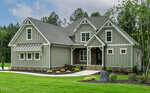 A modern, single-family house at 3913 Cedar Knolls in Youngsville features gray siding, white trim, and a gabled roof on a well-manicured lawn with shrubs and a stone path, surrounded by trees under a partly cloudy sky.