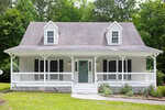 A light gray house at 657 Lakeview Drive in Stem features a covered front porch, two dormer windows, white railings, and a green front door, surrounded by grass and trees in the background.