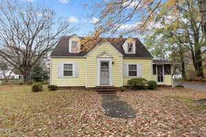 A small, yellow, two-story house with white trim and shutters at 345 Henderson Street, Oxford. It features a central front door and a screened porch on the right side, surrounded by a yard with scattered autumn leaves and some trees.