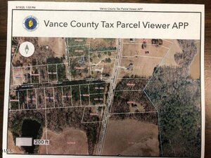 A printed map titled "Vance County Tax Parcel Viewer APP" shows various land parcels, roads, wooded areas, and a scale of 200 feet near 145 Daniel Boone Trail, Henderson. Some parcels have red numbers, and a directional arrow is included.