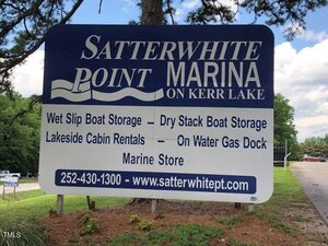 Large sign for Satterwhite Point Marina on Kerr Lake advertising wet slip boat storage, dry stack boat storage, lakeside cabin rentals, on water gas dock, marine store, a phone number, and website.