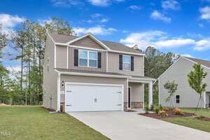 Charming two-story beige home at 111 Rhino Bend, Oxford, with white trim, an attached two-car garage, covered front porch, and concrete driveway. The landscaped yard features grass, small plants, young trees, and a partly cloudy sky.