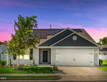 A single-story house at 1561 Dorsett Lane in Creedmoor with solar panels on the roof, gray siding, a covered entryway, white garage door, small front lawn, and a tree, photographed at sunset.
