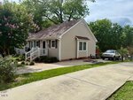 A small beige house with white trim and a front porch sits beside a concrete driveway at 120 W Front Street, Oxford. A silver vehicle is parked near the house, and there are trees and green shrubs in the yard.
