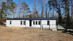 A single-story white house with a black metal roof, large windows, and a small porch with steps sits at 421 General Green Road, Kittrell, surrounded by bare trees and dry grass under a clear blue sky.