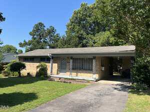 Charming single-story brick house at 417 Sunnyview Road, Henderson, featuring a covered front porch and carport. The mowed lawn and landscaped trees create inviting curb appeal under a clear blue sky.