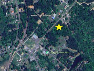 A satellite view of a suburban area with trees, roads, and houses. Landmarks labeled are Agape Worship Center (top left) and Jack Day Kiddie Park (bottom center). A large yellow star marks a wooded area near a main road.