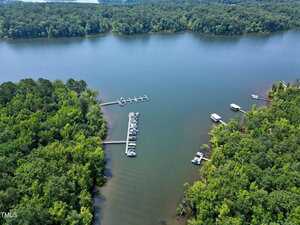 Aerial view of a lake with two docks extending into the water, several boats moored at the docks, and dense green forest surrounding the shoreline.