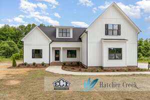 A modern white two-story house with black trim, multiple windows, and a gable roof sits on Lot 19 Spring Grove Drive in Oxford, set on a bare dirt lot with minimal landscaping. ECI Construction and Hatcher Creek logos are overlaid at the bottom.