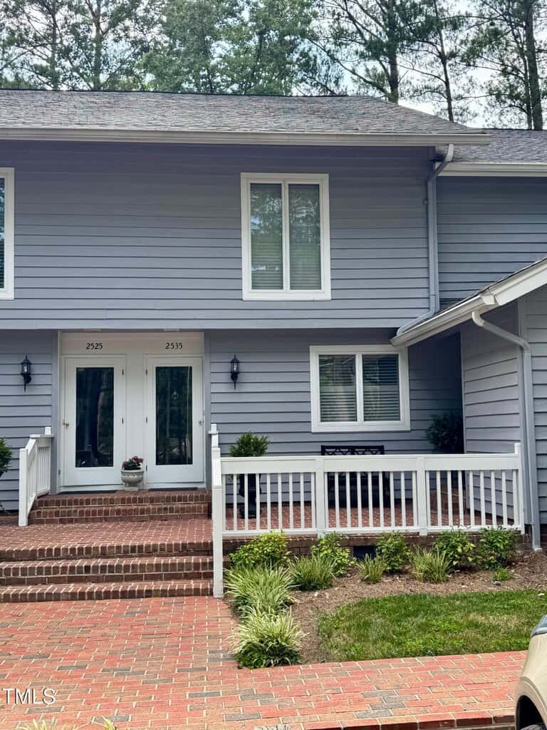 A two-story house at 2535 Fairway Drive with light blue horizontal siding, white trim, and a brick walkway. There are double entry doors, a front porch with a railing, and small green shrubs along the walkway in Henderson.