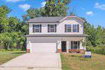 A two-story suburban house with white siding, black roof shingles, a double garage, and a front lawn. Located at 110 Hays Street in Oxford, it features a real estate sign near the driveway with trees and blue sky in the background.
