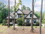 Two-story house with gray siding, black trim, and gabled roof at 3601 Carole Court in Wake Forest, surrounded by trees and shrubs. A concrete walkway leads to the front door, with a lawn covered in pine straw mulch in a wooded suburban setting.