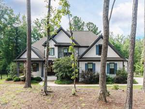 Two-story house with gray siding, black trim, and gabled roof at 3601 Carole Court in Wake Forest, surrounded by trees and shrubs. A concrete walkway leads to the front door, with a lawn covered in pine straw mulch in a wooded suburban setting.